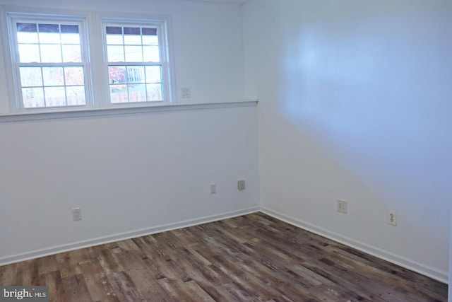 spare room with dark wood-type flooring and baseboards