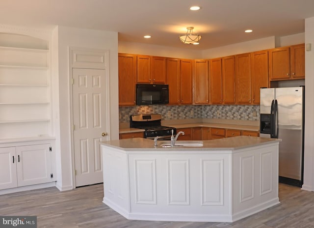 kitchen with stainless steel appliances, wood finished floors, a sink, and light countertops