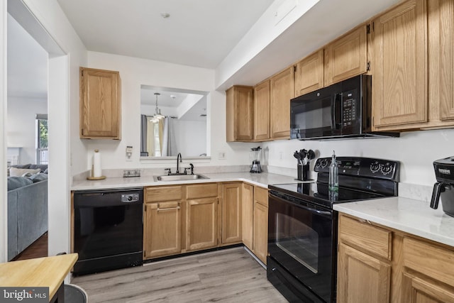 kitchen featuring black appliances, light wood-style flooring, light countertops, and a sink