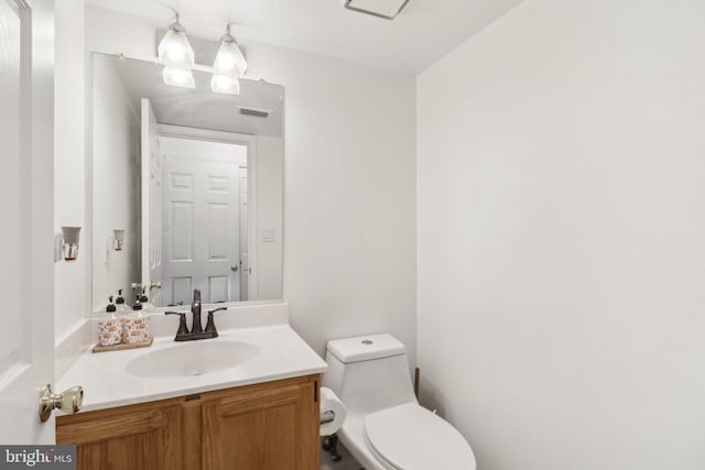 half bathroom featuring visible vents, vanity, and toilet