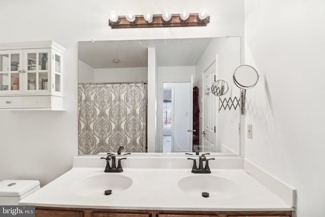 full bath featuring a sink, toilet, and double vanity