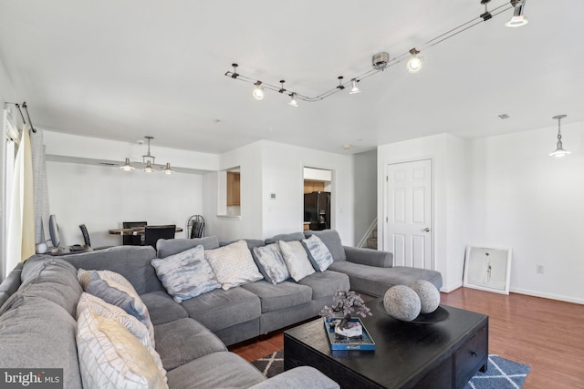 living room with visible vents, stairs, baseboards, and wood finished floors