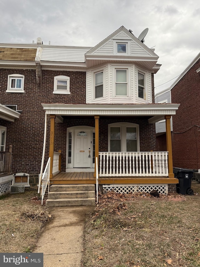 townhome / multi-family property featuring covered porch and brick siding