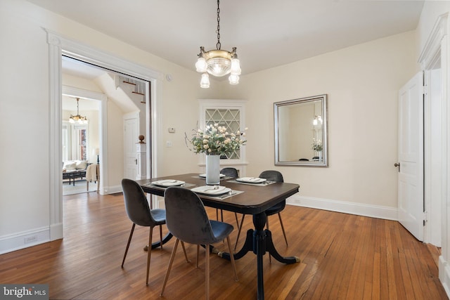 dining area with baseboards, wood finished floors, and a notable chandelier