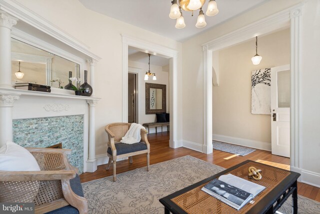 living area featuring baseboards, an inviting chandelier, and wood finished floors