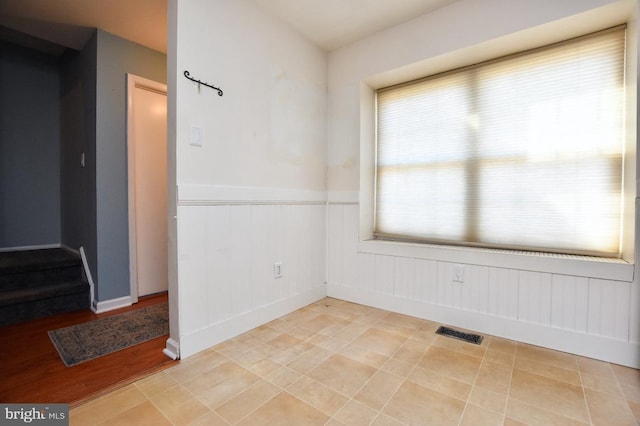 spare room with visible vents and a wainscoted wall