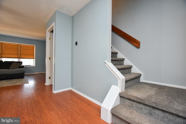 staircase featuring baseboards and wood finished floors