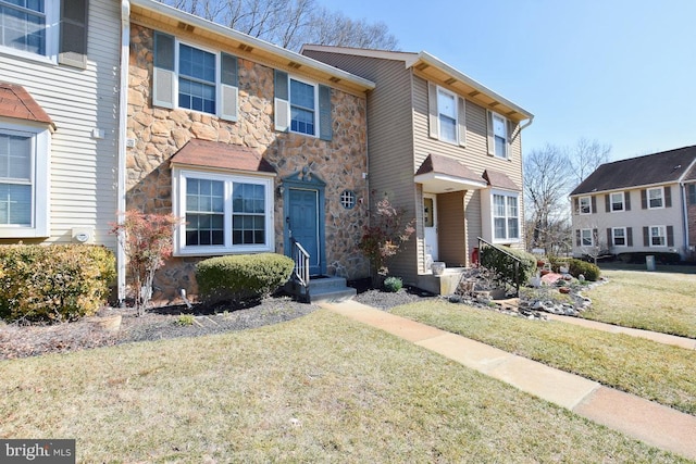 townhome / multi-family property featuring stone siding and a front yard