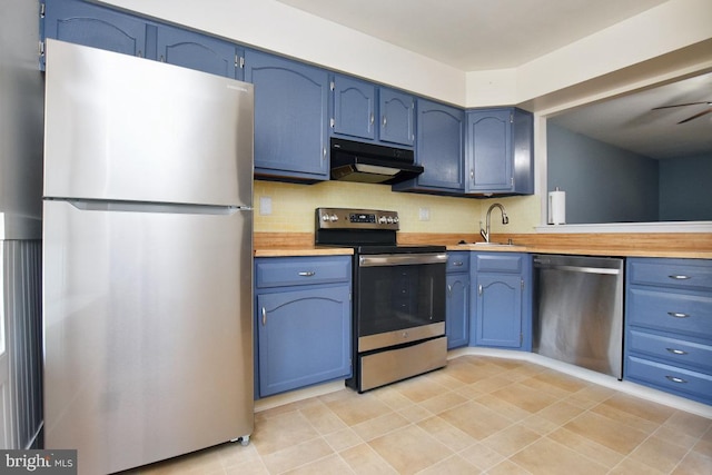 kitchen featuring under cabinet range hood, blue cabinetry, appliances with stainless steel finishes, and a sink