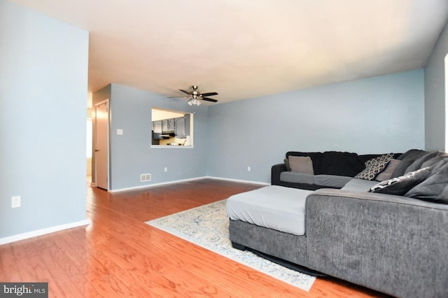 living area featuring ceiling fan, visible vents, baseboards, and wood finished floors