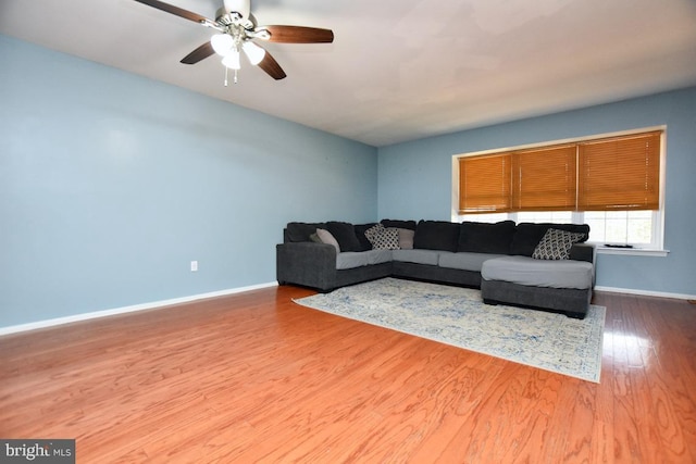 living area featuring wood finished floors, baseboards, and ceiling fan