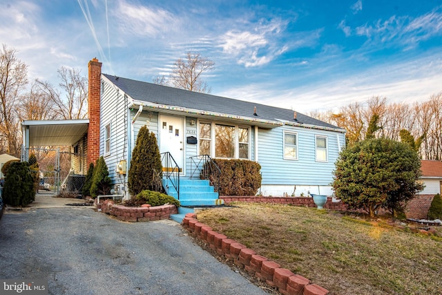 view of front of property featuring an attached carport, a chimney, and a front yard