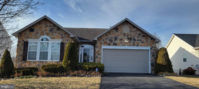 view of front of home with a garage, stone siding, and driveway