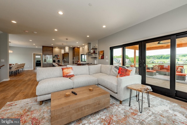 living room featuring baseboards, light wood-style flooring, and recessed lighting