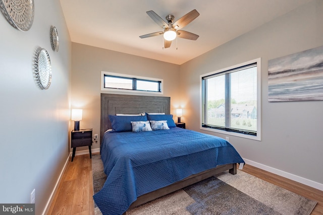 bedroom featuring multiple windows, baseboards, and wood finished floors