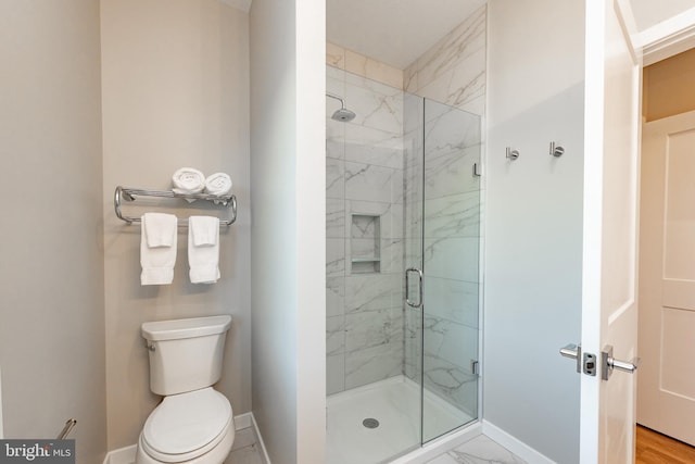 bathroom featuring toilet, marble finish floor, a marble finish shower, and baseboards