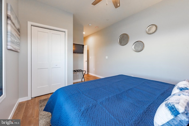 bedroom with a closet, light wood-style flooring, a ceiling fan, vaulted ceiling, and baseboards