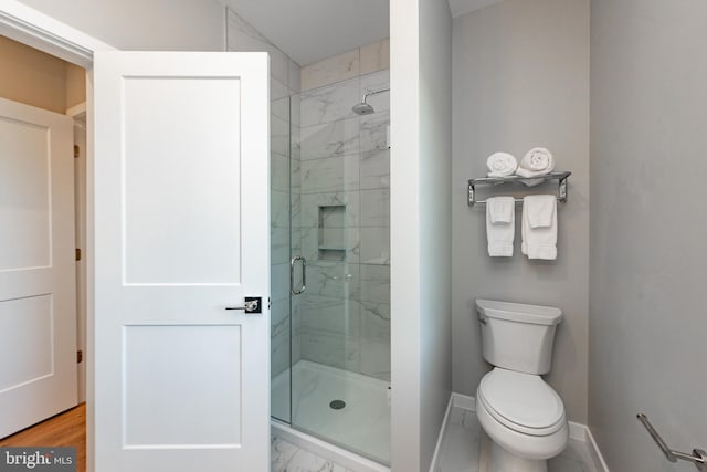 bathroom with marble finish floor, a shower stall, toilet, and baseboards