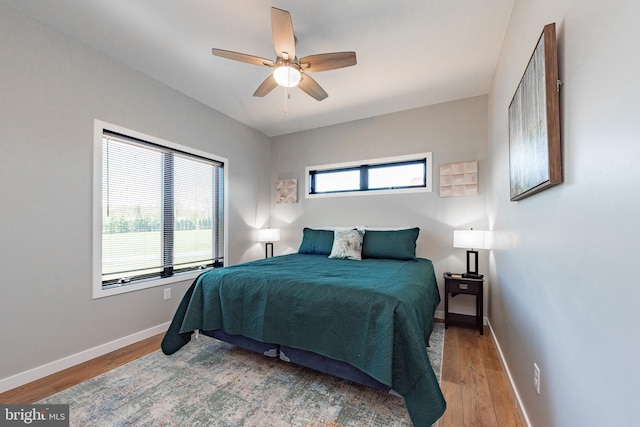 bedroom with multiple windows, baseboards, and wood finished floors