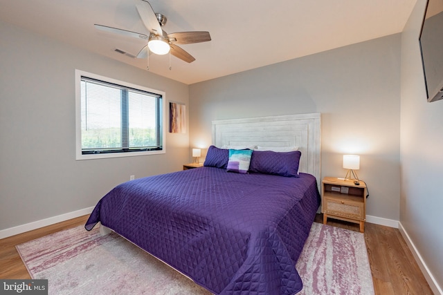 bedroom with a ceiling fan, baseboards, visible vents, and wood finished floors