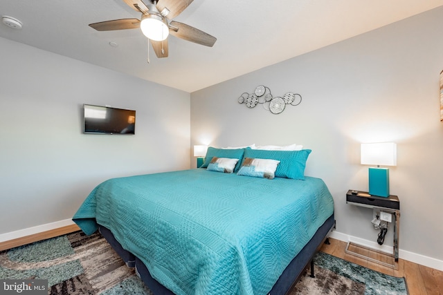 bedroom featuring lofted ceiling, a ceiling fan, baseboards, and wood finished floors