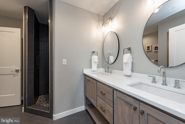 full bath featuring double vanity, baseboards, a tile shower, and a sink