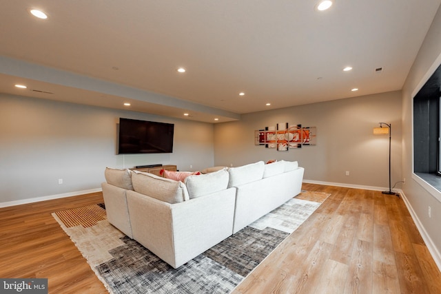 living room featuring recessed lighting, baseboards, and light wood finished floors