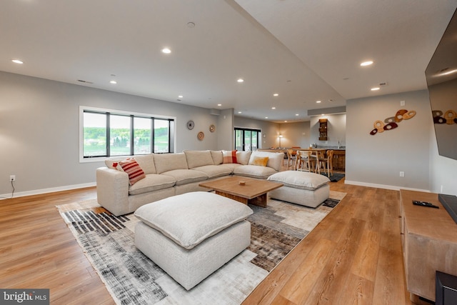 living room featuring light wood-style flooring, baseboards, and recessed lighting