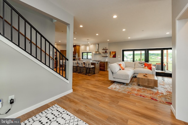 living area featuring baseboards, stairway, wood finished floors, and recessed lighting