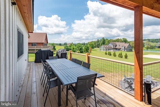 wooden terrace with outdoor dining space, a grill, and a yard