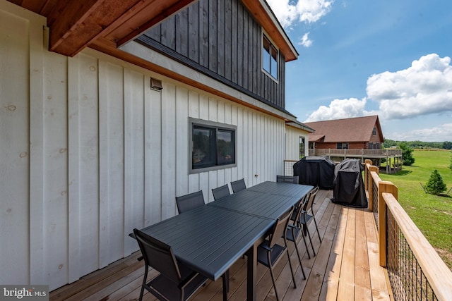 wooden deck featuring a yard, outdoor dining area, and area for grilling