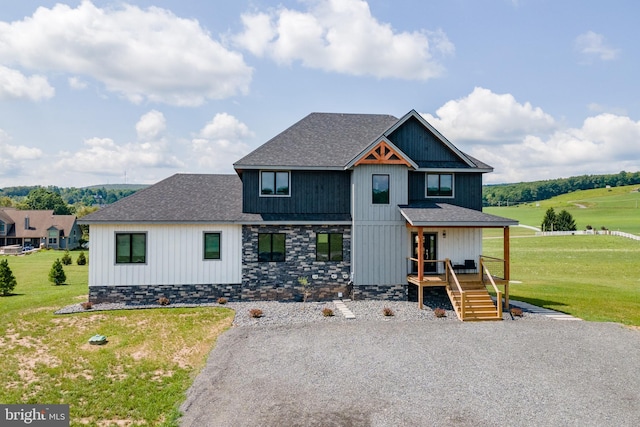 view of front facade featuring covered porch, stone siding, a front lawn, and a shingled roof