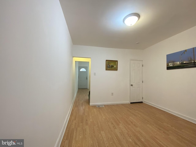 unfurnished room featuring light wood-type flooring, baseboards, and visible vents