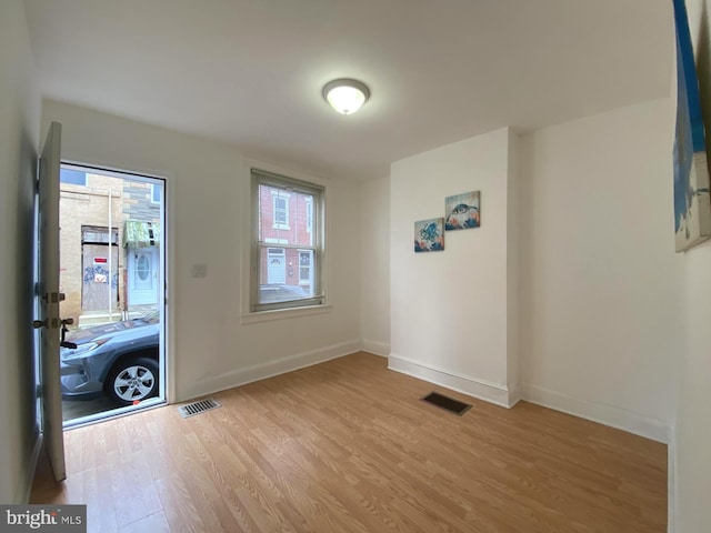 foyer entrance featuring light wood-type flooring, baseboards, and visible vents