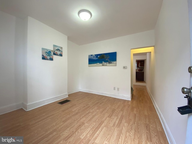 spare room with light wood finished floors, visible vents, and baseboards