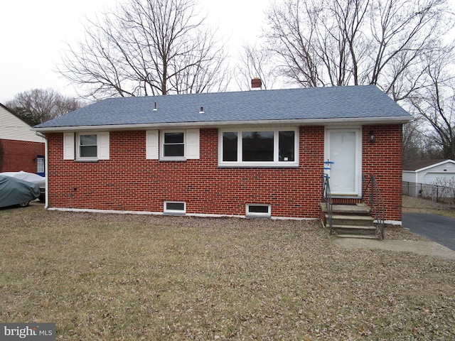 view of front of house featuring entry steps, brick siding, roof with shingles, and a front yard