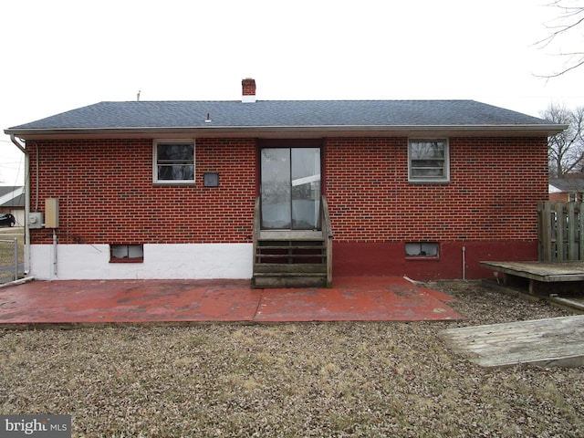 rear view of property with entry steps, brick siding, a chimney, and a patio area