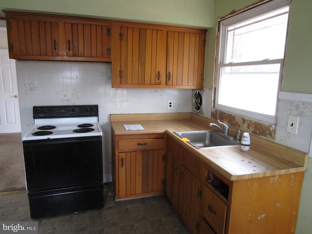 kitchen with tasteful backsplash, range with electric stovetop, a sink, and brown cabinets