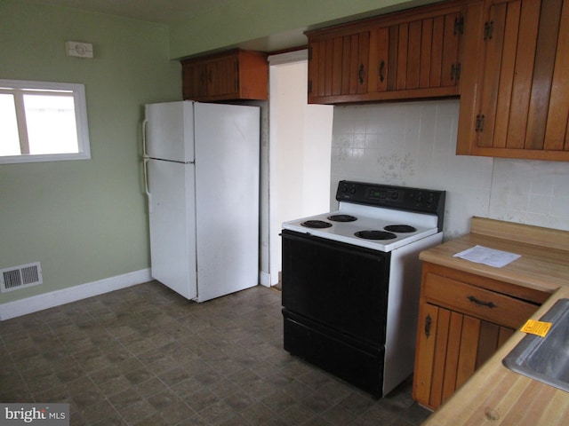 kitchen featuring tasteful backsplash, visible vents, freestanding refrigerator, light countertops, and range with electric stovetop