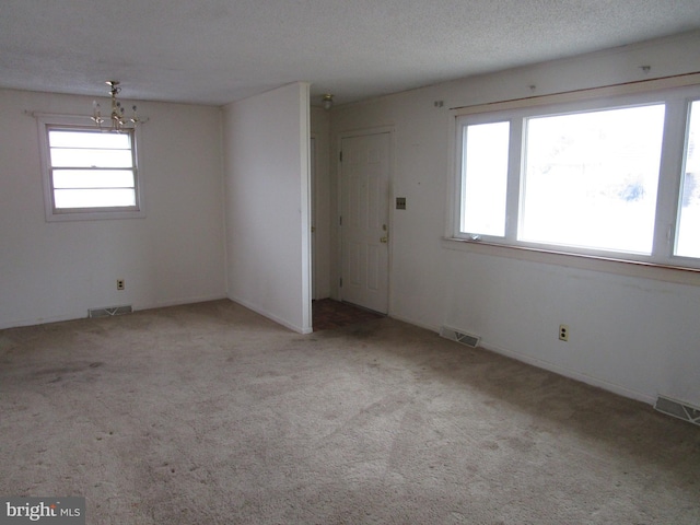 interior space with carpet floors, a chandelier, visible vents, and a textured ceiling