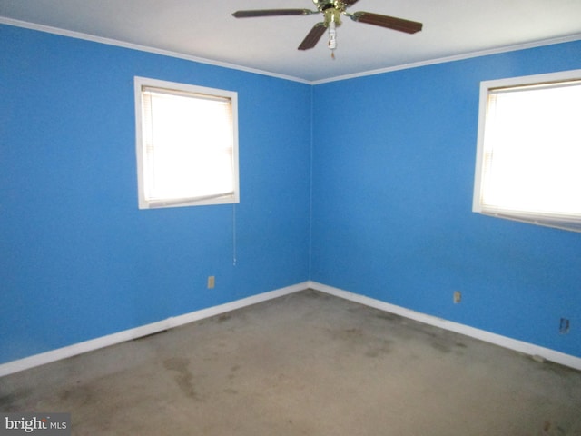 carpeted empty room featuring ceiling fan, baseboards, and crown molding