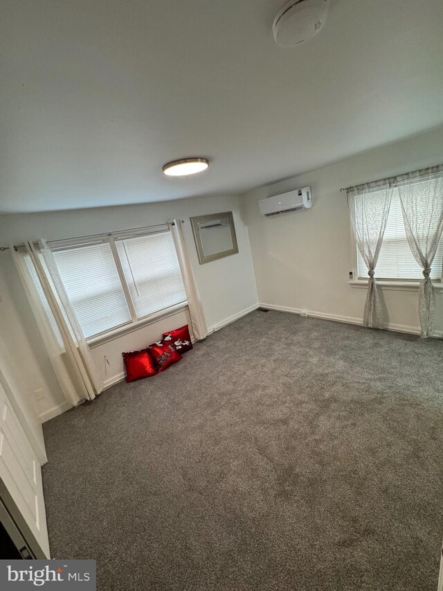 playroom with dark colored carpet, a wall mounted AC, and baseboards