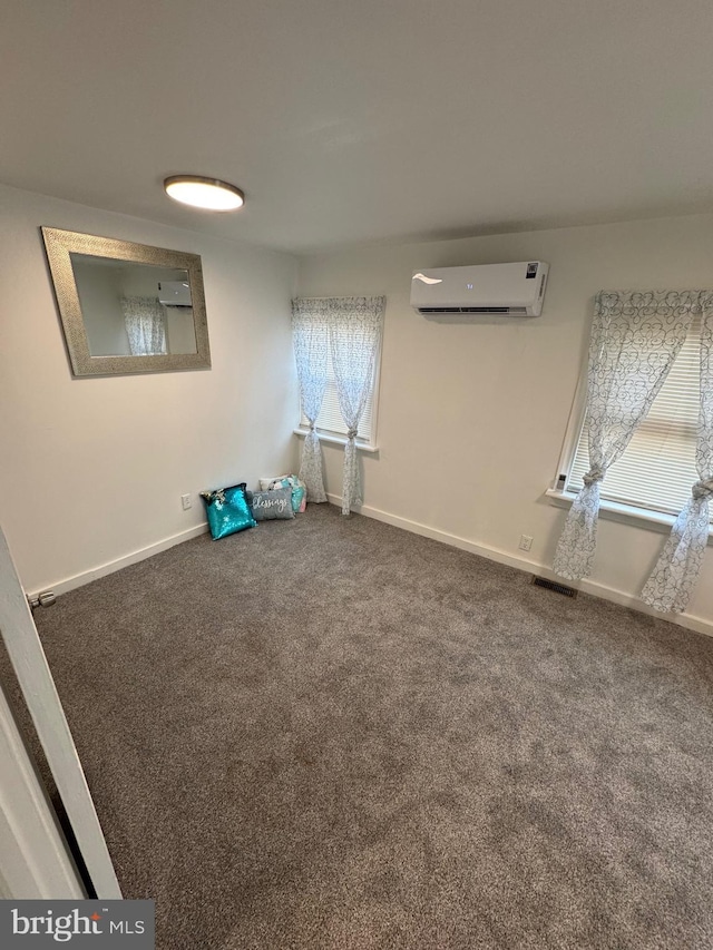 carpeted spare room with baseboards, visible vents, and an AC wall unit