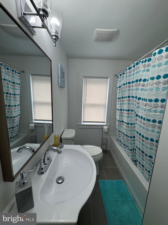 bathroom with toilet, a healthy amount of sunlight, a sink, and tile patterned floors