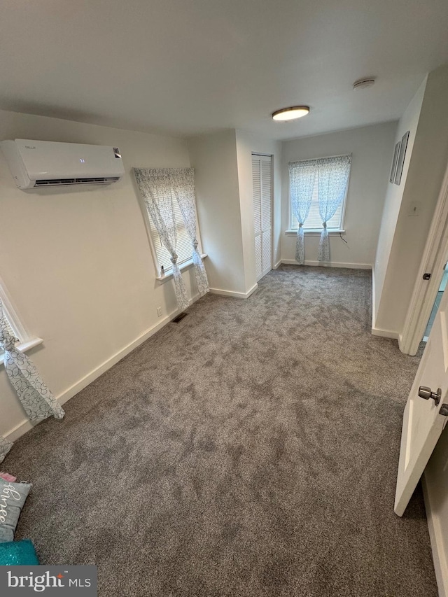 interior space featuring carpet flooring, visible vents, baseboards, and a wall mounted AC