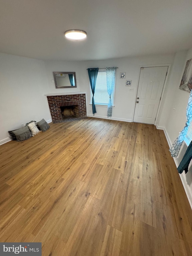 unfurnished living room featuring baseboards, a fireplace, and hardwood / wood-style floors