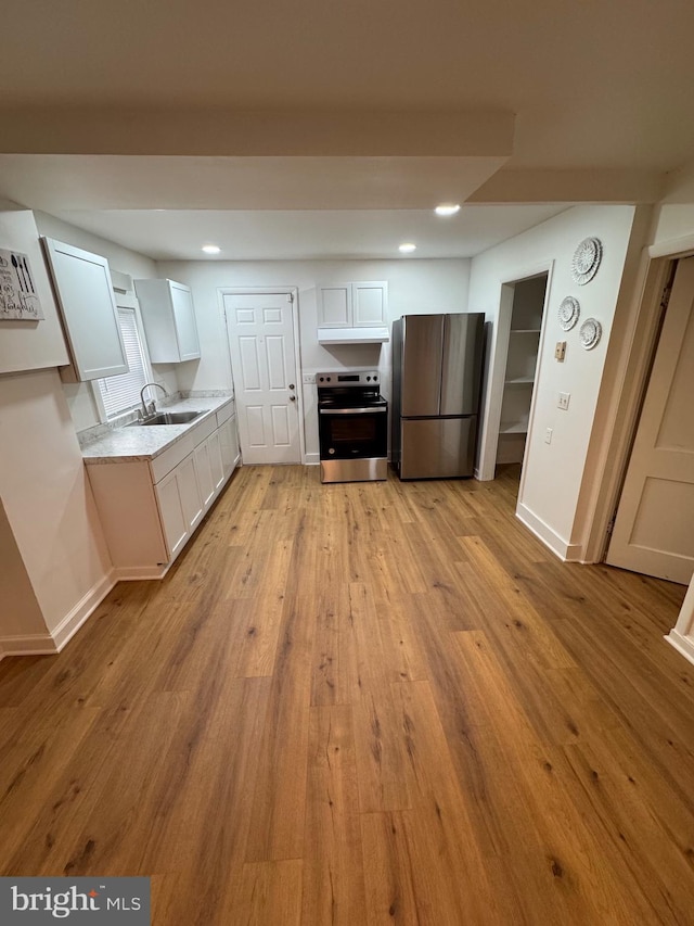 kitchen featuring a sink, baseboards, white cabinets, appliances with stainless steel finishes, and light wood finished floors