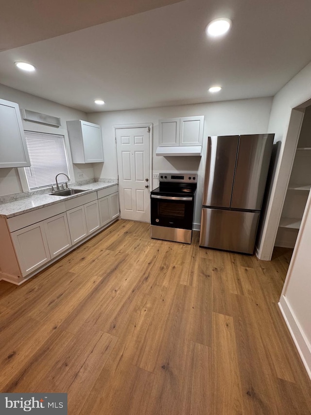 kitchen with appliances with stainless steel finishes, light wood-type flooring, a sink, and recessed lighting