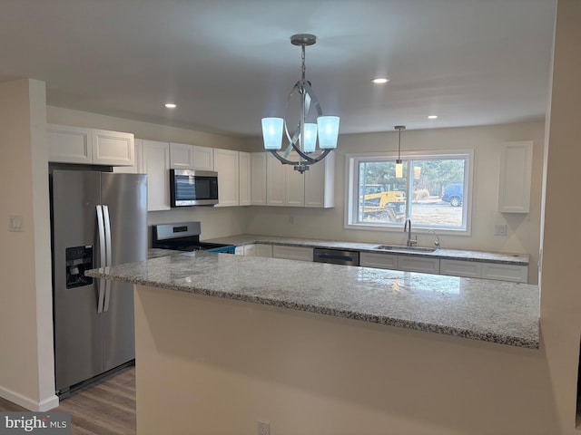 kitchen featuring stainless steel appliances, white cabinets, a sink, and light stone counters