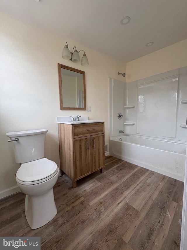 full bath featuring shower / bathtub combination, toilet, wood finished floors, vanity, and baseboards